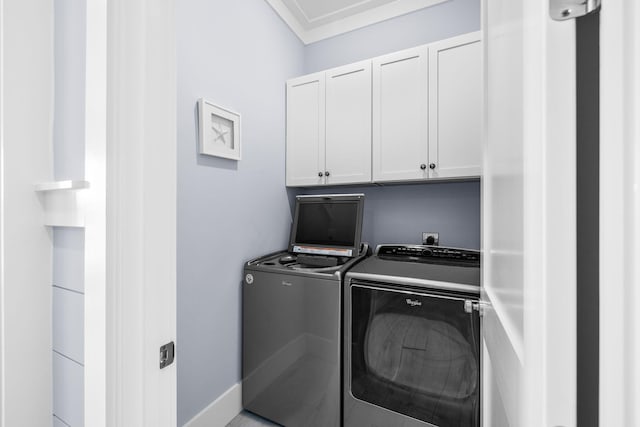 washroom featuring cabinet space, ornamental molding, and washer and clothes dryer