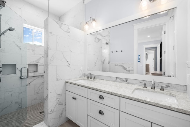 bathroom with double vanity, a marble finish shower, and a sink