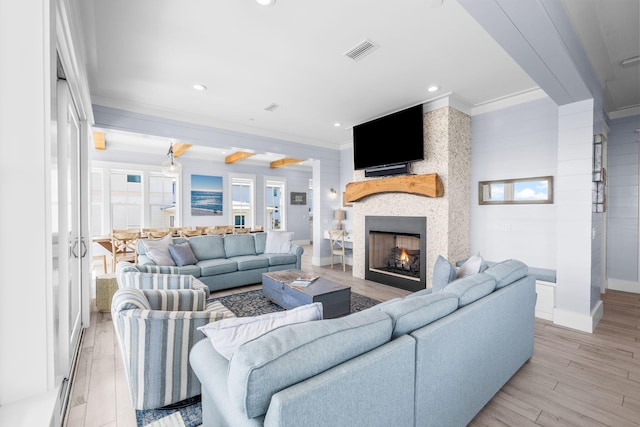 living area with light wood finished floors, visible vents, baseboards, ornamental molding, and a lit fireplace