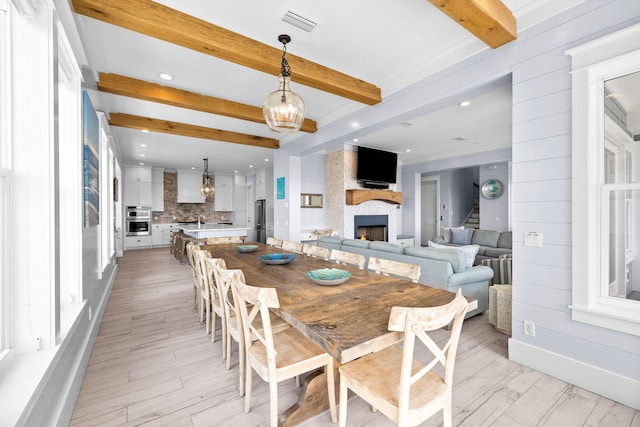 dining space with a fireplace, recessed lighting, light wood-style flooring, stairway, and beamed ceiling