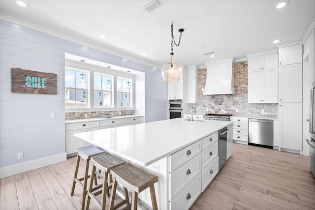 kitchen with premium range hood, a sink, visible vents, light countertops, and appliances with stainless steel finishes