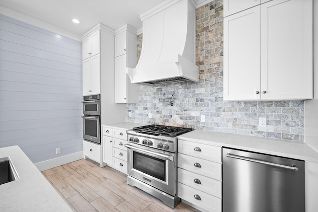 kitchen featuring stainless steel appliances, light countertops, and premium range hood