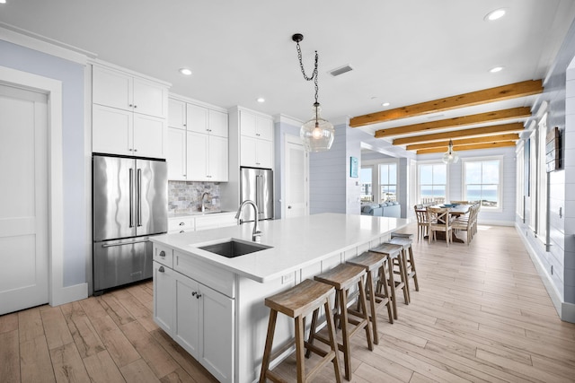 kitchen with tasteful backsplash, a sink, light wood finished floors, and high end refrigerator