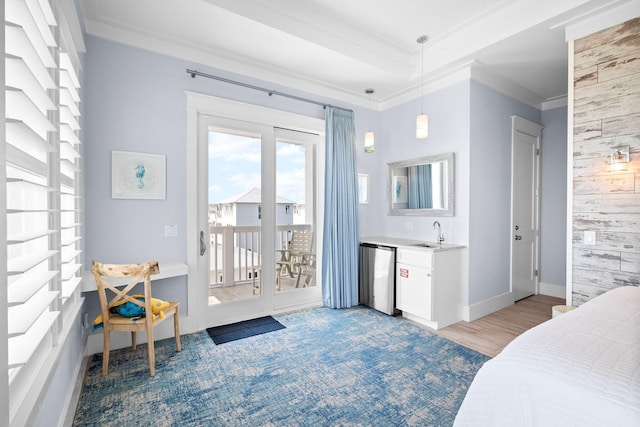 bedroom with baseboards, access to exterior, a tray ceiling, crown molding, and a sink