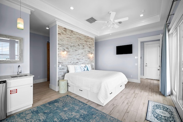 bedroom featuring ornamental molding, a tray ceiling, visible vents, and light wood finished floors