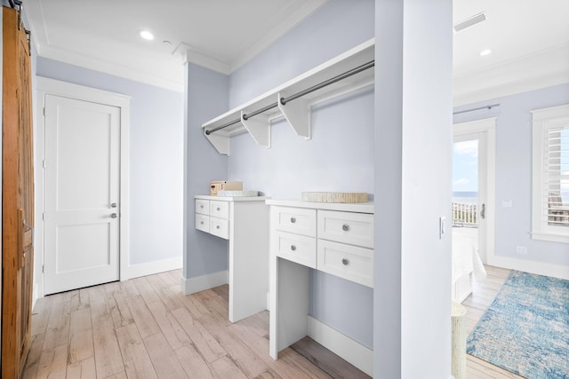 spacious closet with light wood-type flooring, a barn door, and visible vents