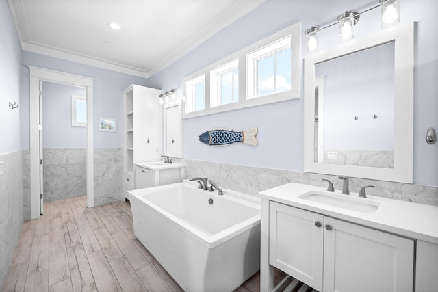 full bathroom with a wainscoted wall, wood finished floors, a sink, tile walls, and crown molding