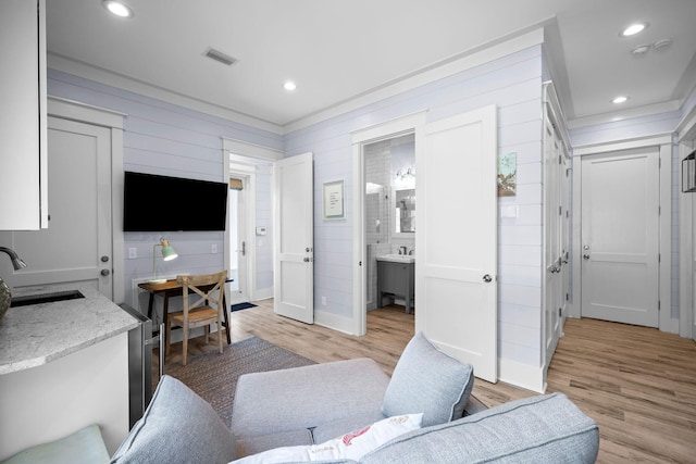 living area with crown molding, recessed lighting, visible vents, and light wood-style floors