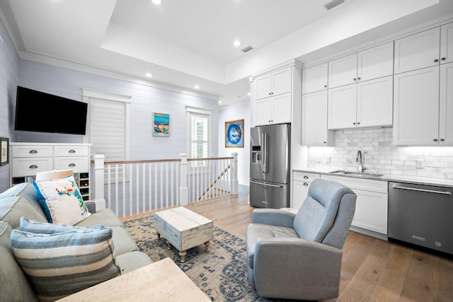 living room featuring a tray ceiling, visible vents, recessed lighting, and hardwood / wood-style flooring