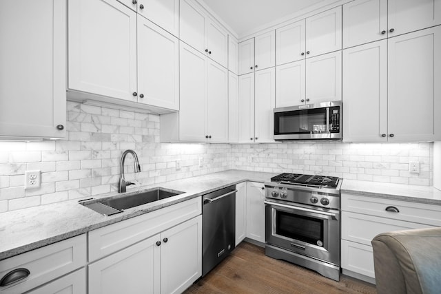 kitchen with stainless steel appliances, backsplash, a sink, and white cabinetry