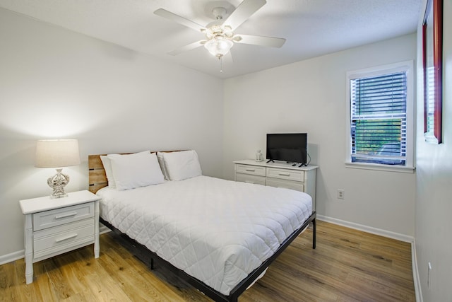 bedroom featuring ceiling fan, light wood-style flooring, and baseboards