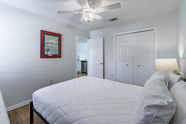 bedroom with ceiling fan, wood finished floors, visible vents, baseboards, and a closet