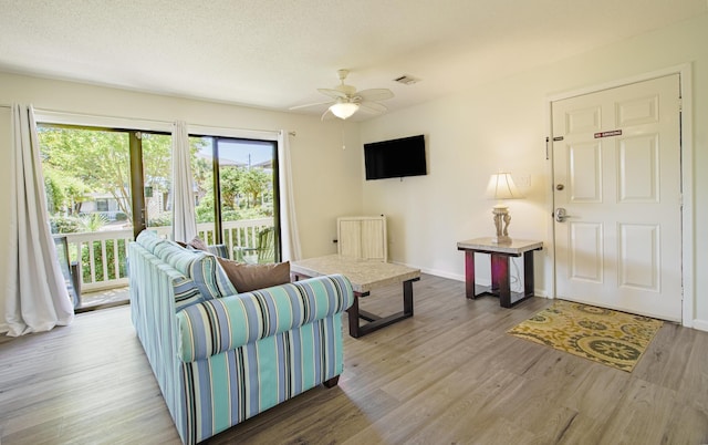 living area featuring visible vents, ceiling fan, a textured ceiling, wood finished floors, and baseboards