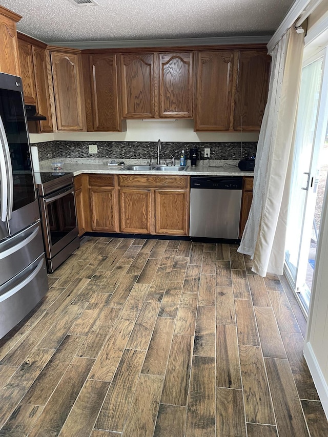 kitchen with a sink, appliances with stainless steel finishes, wood tiled floor, and light countertops