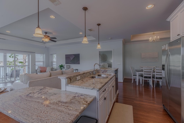 kitchen with a kitchen island with sink, a sink, white cabinetry, stainless steel refrigerator with ice dispenser, and a tray ceiling