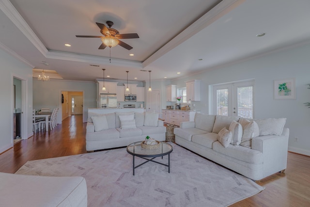 living room featuring a tray ceiling, french doors, baseboards, and wood finished floors