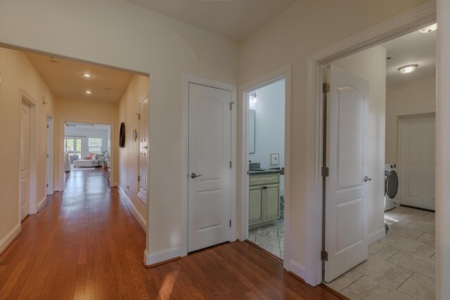 hallway with washer / dryer, baseboards, and wood finished floors