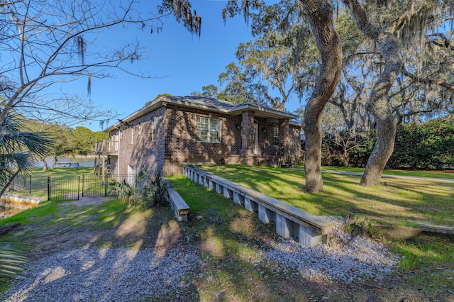 view of front of property with brick siding, a water view, fence, a gate, and a front lawn