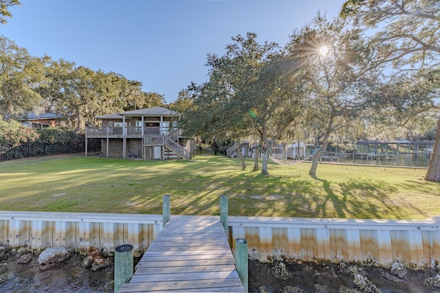 dock area with a deck with water view, a lawn, and stairs