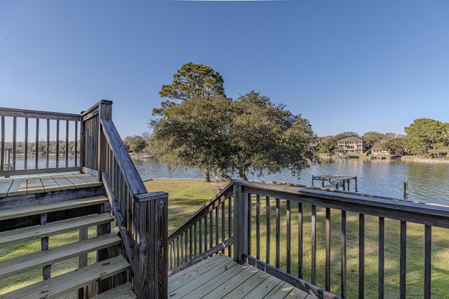 deck with a dock, a water view, and a yard