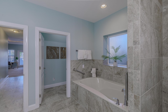 bathroom with recessed lighting, baseboards, and a bath