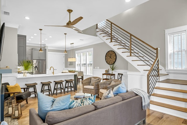 living room with stairs, a wealth of natural light, and light wood-style floors