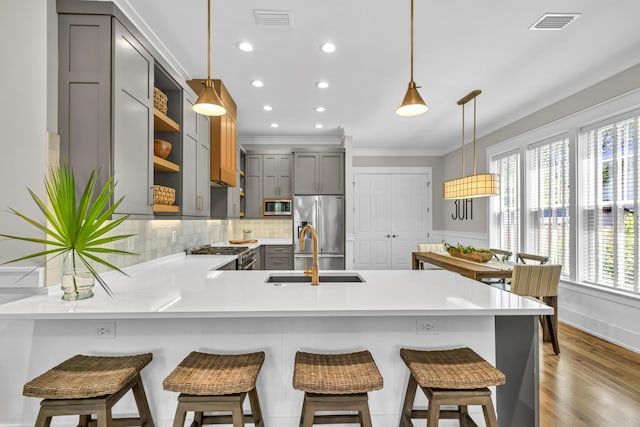 kitchen featuring gray cabinetry, a peninsula, a sink, visible vents, and appliances with stainless steel finishes