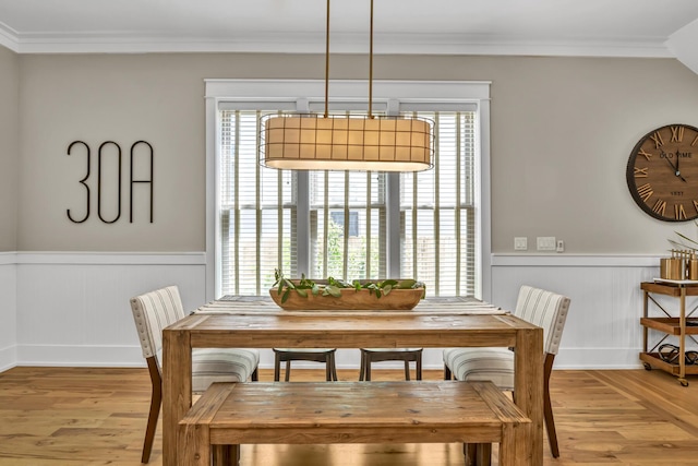 dining area featuring a wainscoted wall, ornamental molding, and wood finished floors