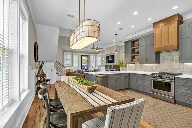 kitchen with decorative backsplash, ornamental molding, gray cabinets, stainless steel appliances, and light countertops