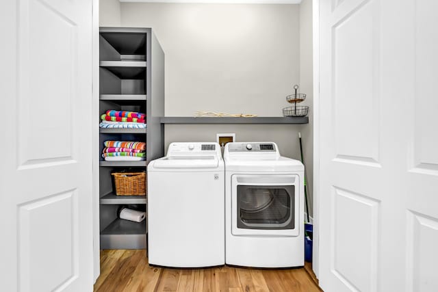 clothes washing area featuring washer and dryer, laundry area, and wood finished floors