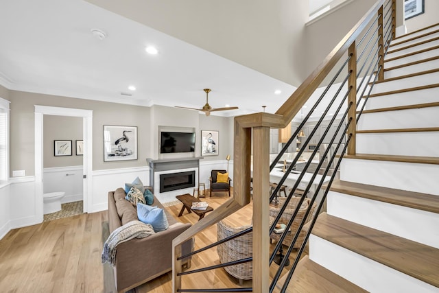 living area featuring crown molding, wainscoting, a fireplace, and stairs