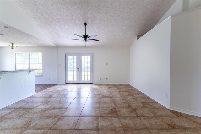 tiled spare room with baseboards, vaulted ceiling, a textured ceiling, and french doors