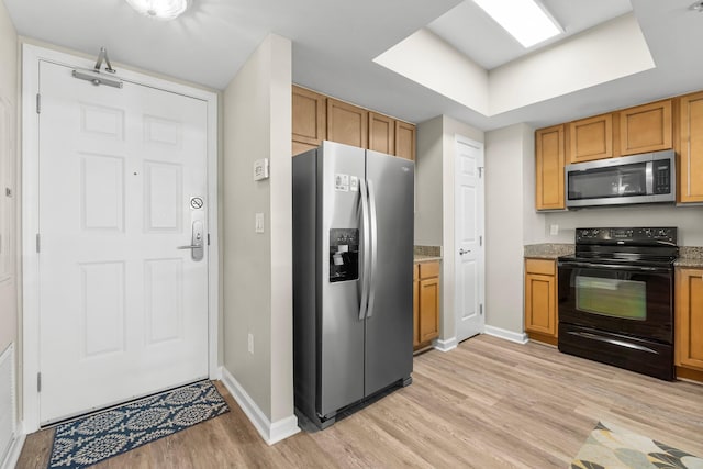 kitchen with baseboards, appliances with stainless steel finishes, light wood-style flooring, and light stone countertops