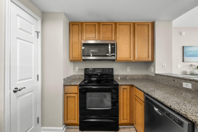 kitchen with stainless steel appliances, baseboards, brown cabinets, and dark stone countertops