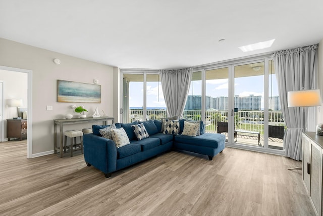 living room with light wood-type flooring, plenty of natural light, expansive windows, and a city view