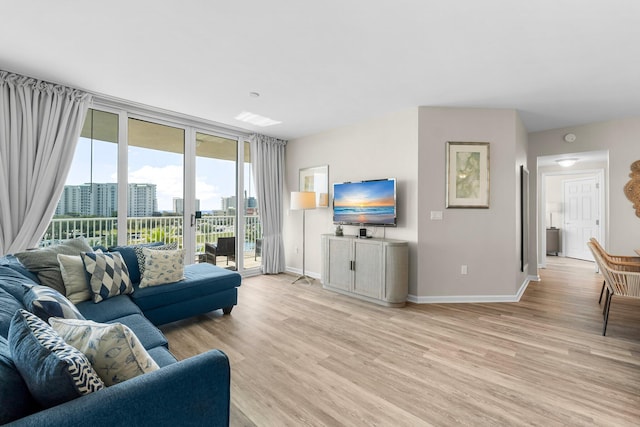 living area with a wall of windows, light wood-type flooring, and baseboards