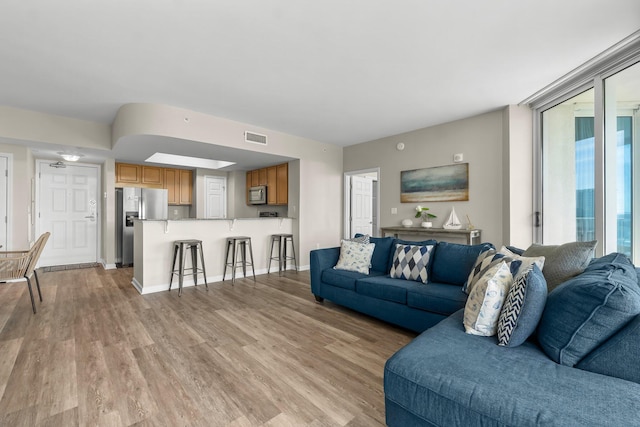 living area featuring light wood-type flooring, visible vents, and baseboards