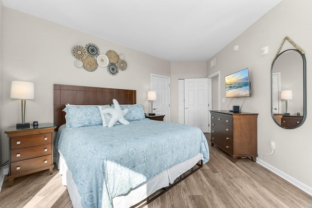 bedroom featuring light wood-style floors, visible vents, and baseboards