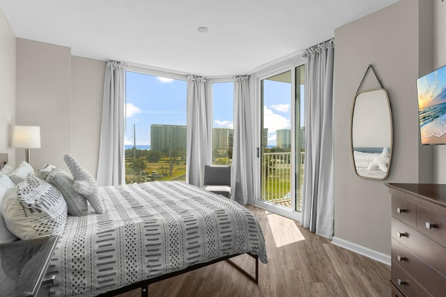 bedroom with access to exterior, baseboards, and wood finished floors