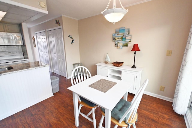 dining space featuring crown molding, dark wood finished floors, and baseboards