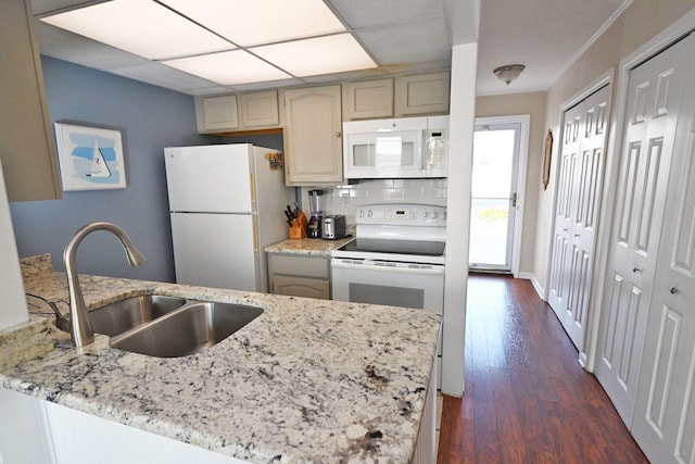 kitchen with light stone counters, dark wood finished floors, backsplash, a sink, and white appliances