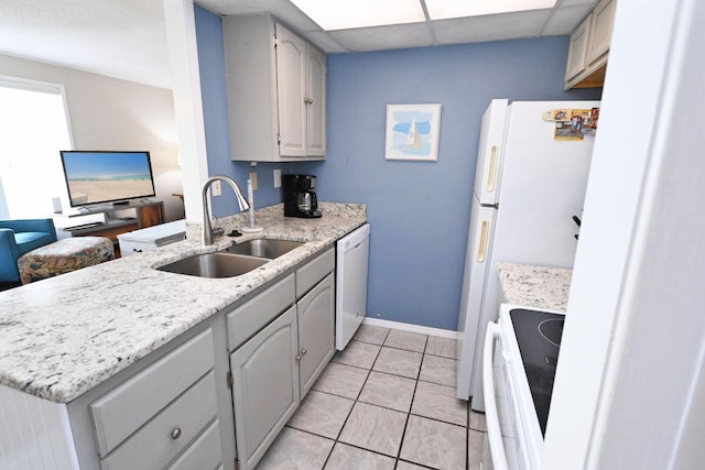 kitchen featuring a paneled ceiling, a sink, white appliances, a peninsula, and baseboards