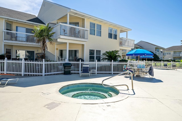 view of swimming pool with fence and a hot tub