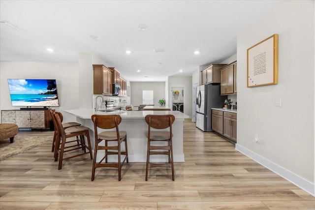 kitchen with appliances with stainless steel finishes, a breakfast bar, light countertops, and a peninsula