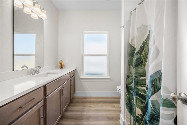 bathroom with toilet, baseboards, wood finished floors, and vanity