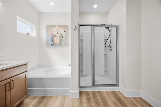 bathroom featuring wood finished floors, a shower stall, vanity, and a bath