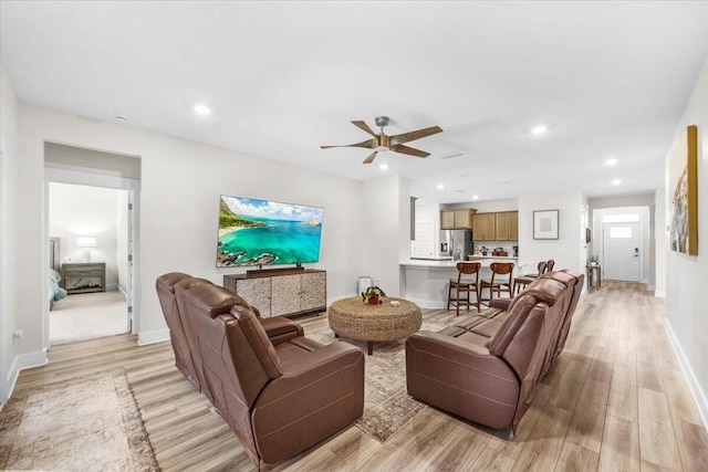 living room featuring baseboards, ceiling fan, light wood-style flooring, and recessed lighting