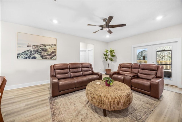 living area featuring light wood finished floors, ceiling fan, baseboards, and french doors