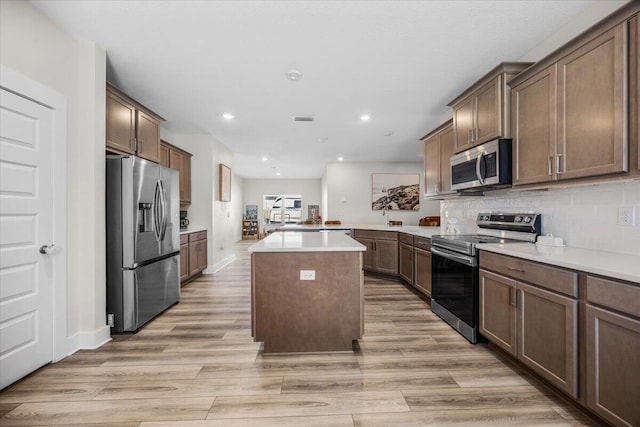 kitchen featuring stainless steel appliances, a center island, light wood-style flooring, and decorative backsplash