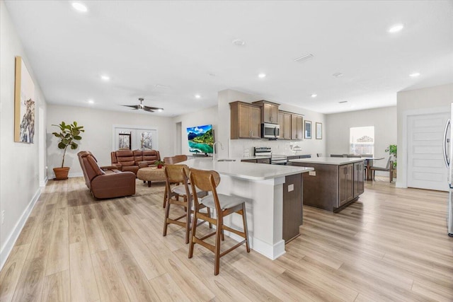 kitchen with a breakfast bar, stainless steel appliances, light countertops, a kitchen island, and a sink